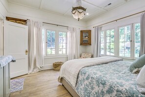 A bedroom with a large bed, a wooden cabinet, and a chandelier.