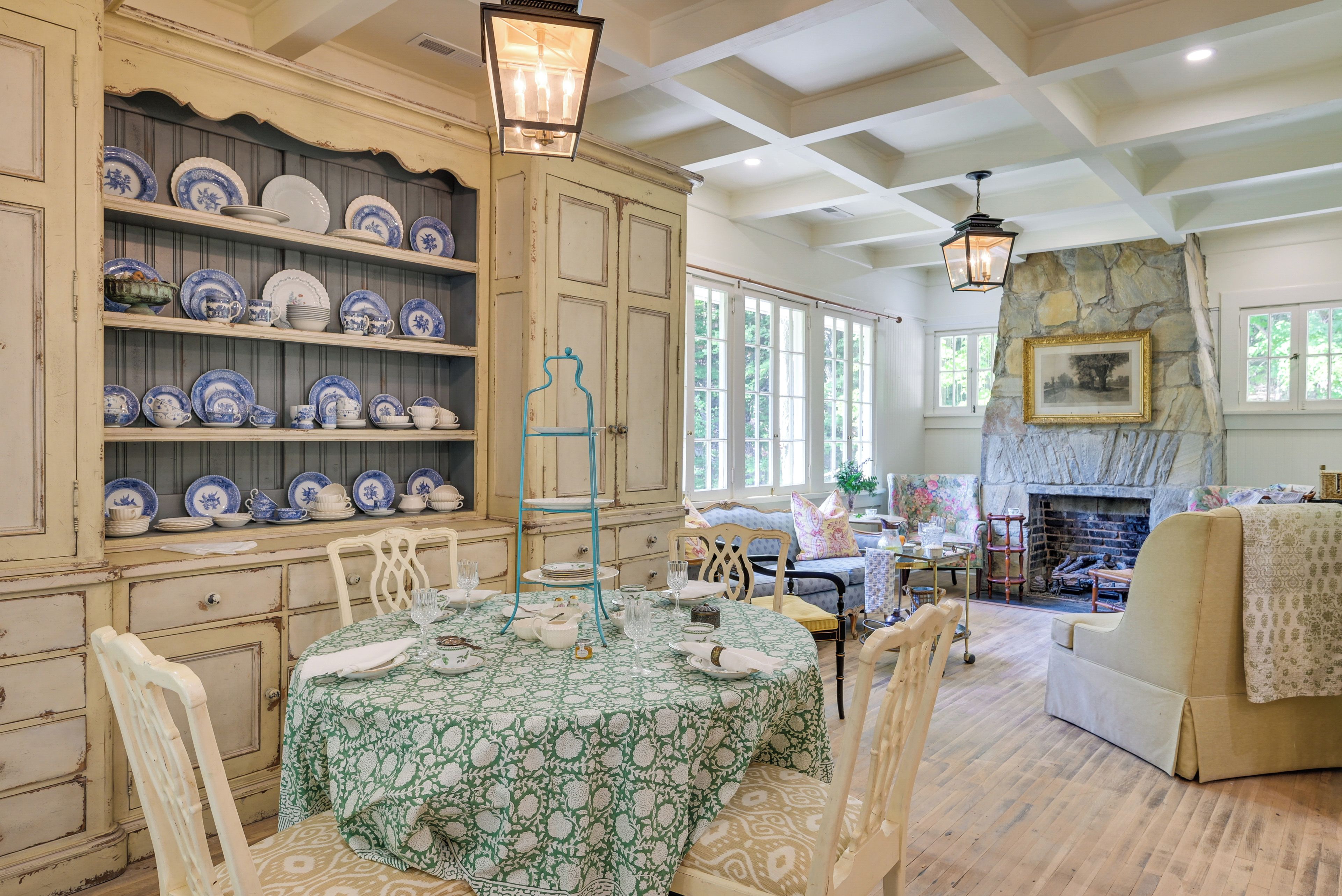 A dining area with a table set for four, surrounded by chairs, and a collection of blue and white plates on shelves.