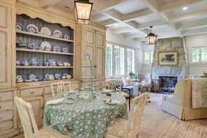 A dining area with a table set for four, surrounded by chairs, and a collection of blue and white plates on shelves.