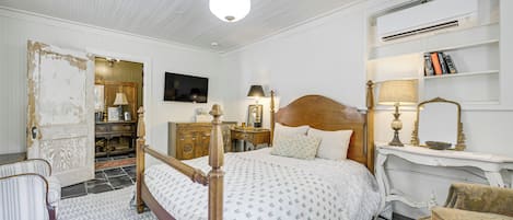 A bedroom with a wooden bed, a nightstand, a dresser, a television, and a bookshelf.