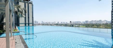 A swimming pool with a cityscape view, surrounded by modern buildings and palm trees.