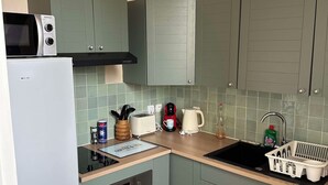 Una cocina compacta equipada con microondas, tostadora, hervidor y lavamanos.
