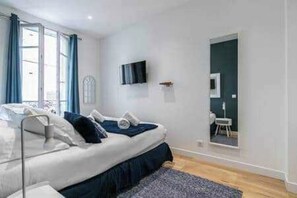 A bedroom with a bed, a TV mounted on the wall, and a window with curtains. - Charming Apartment - 2ch/6p - Montreuil (Montreuil)