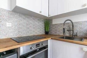 A modern kitchen with a stainless steel oven, a sink, and a speckled backsplash. - Charming Apartment - 2ch/6p - Montreuil (Montreuil)