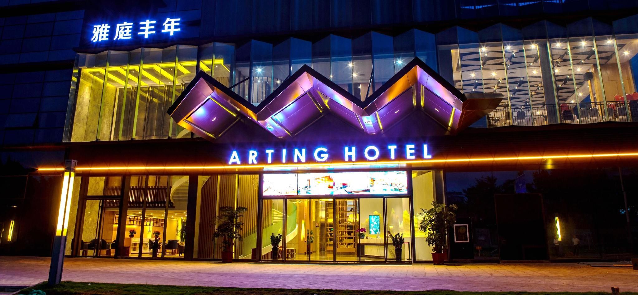 ARTING HOTEL's udvendige facade med et moderne design, der inkluderer et iøjnefaldende neonskilt og en glasfacade.