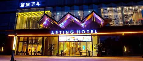 ARTING HOTEL's udvendige facade med et moderne design, der inkluderer et iøjnefaldende neonskilt og en glasfacade.