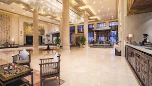 Un vestíbulo amplio con una recepción, zona de estar y columnas decorativas.