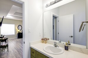 A bathroom with a white sink, a large mirror, and a shower. - Single Home: SpaceX, Hwy 511 & Beaches (Brownsville)