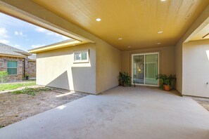 A covered patio area with a concrete floor, a glass door entrance, and potted plants.