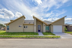 A two-story house with a garage, a front porch, and a well-maintained lawn. - Single Home: SpaceX, Hwy 511 & Beaches (Brownsville)