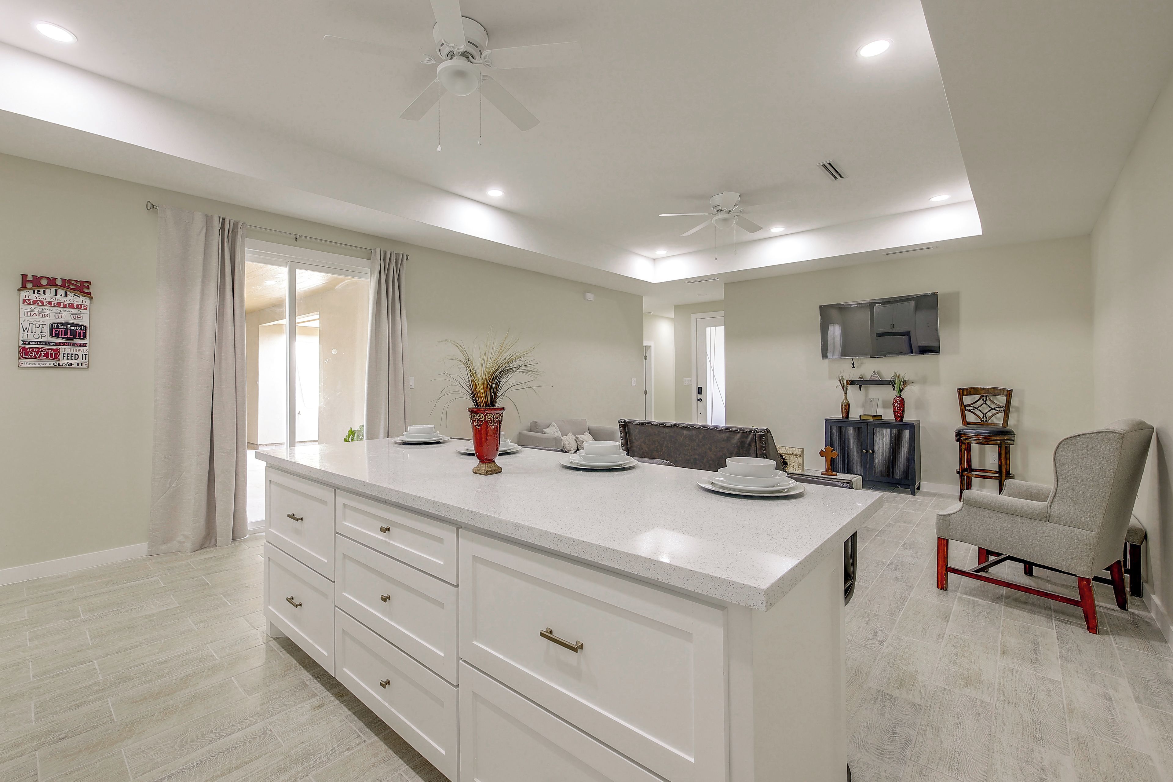 Une cuisine moderne dotée d’un grand îlot central, de meubles blancs et d’un ventilateur de plafond.