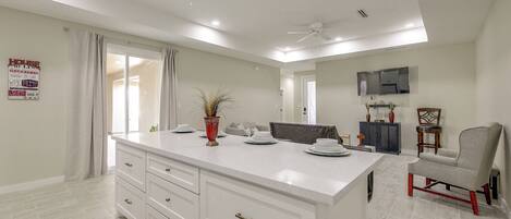 A modern kitchen with a large island, white cabinetry, and a ceiling fan.