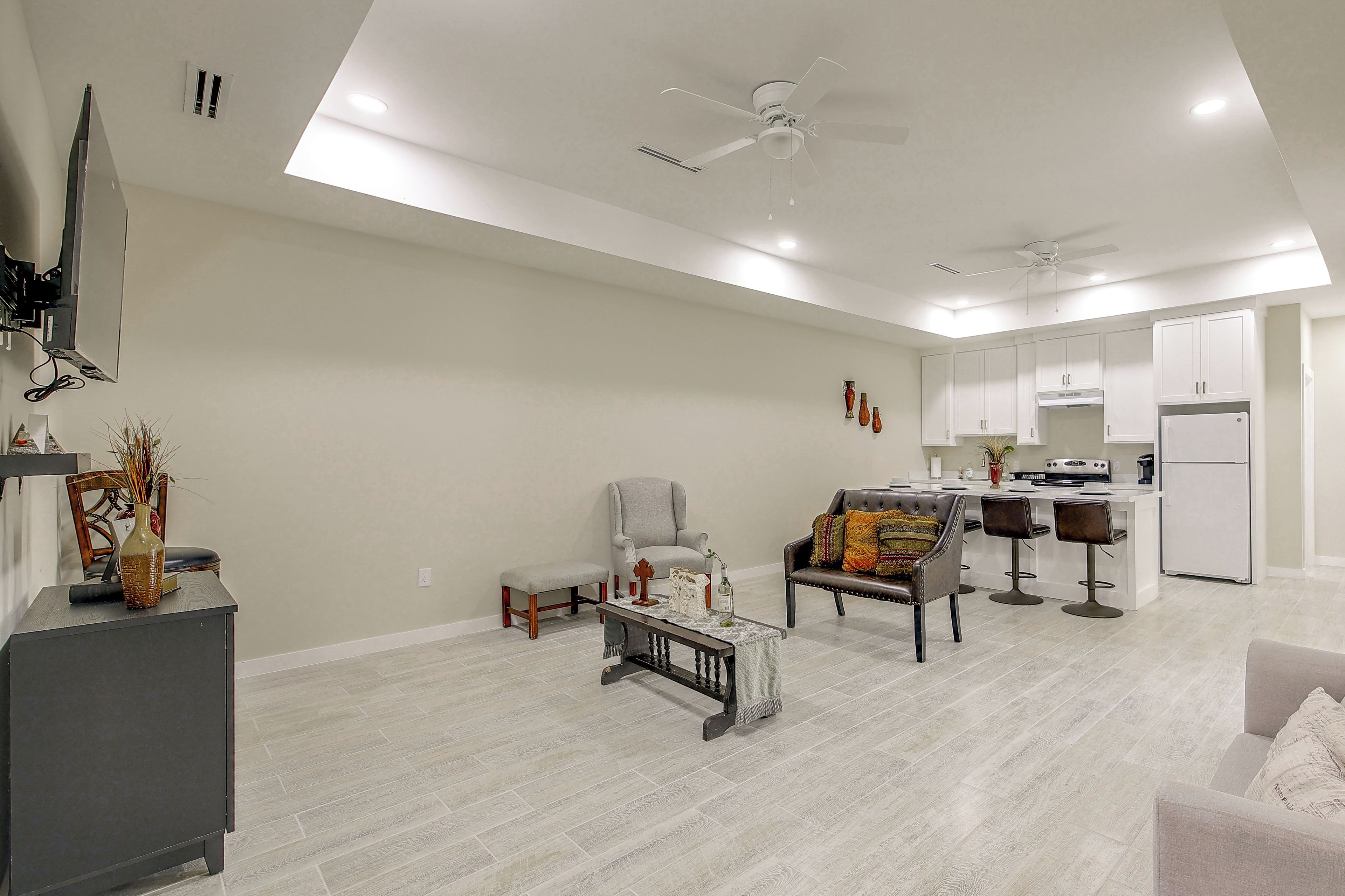 Amplia sala de estar con comedor, sofá, mesa de centro y área de cocina equipada con refrigerador y estufa.