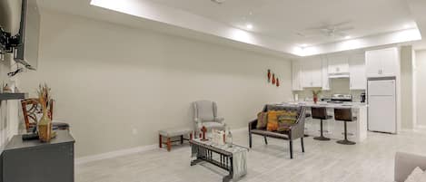 A spacious living area with a dining set, a sofa, a coffee table, and a kitchen area with a refrigerator and a stove.