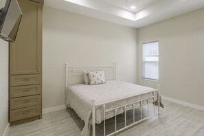 A bedroom with a bed, a wardrobe, a window with blinds, and a ceiling light.