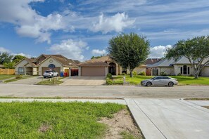 A residential street with houses, a driveway, and a tree.