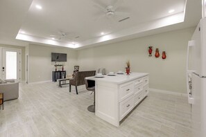 A spacious living area with a central island, a ceiling fan, recessed lighting, a flat-screen TV, and decorative vases on the wall. - Brownsville Home: 9 Mi to Downtown! (Brownsville)
