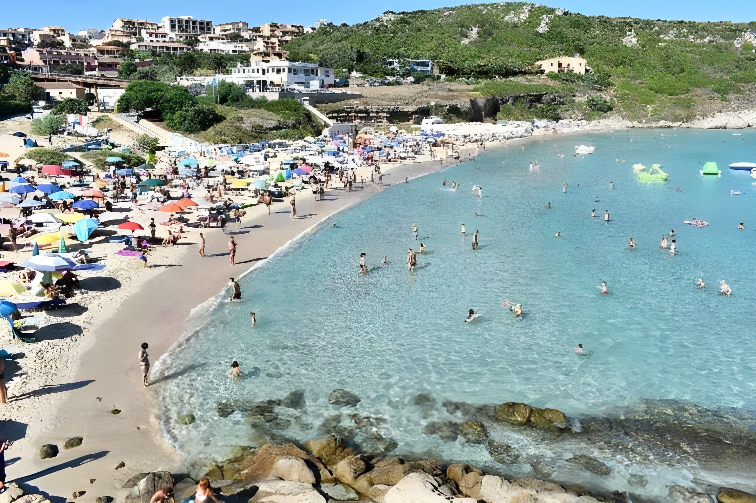 Ein Strand mit klarem Wasser, Sonnenschirmen und Menschen.