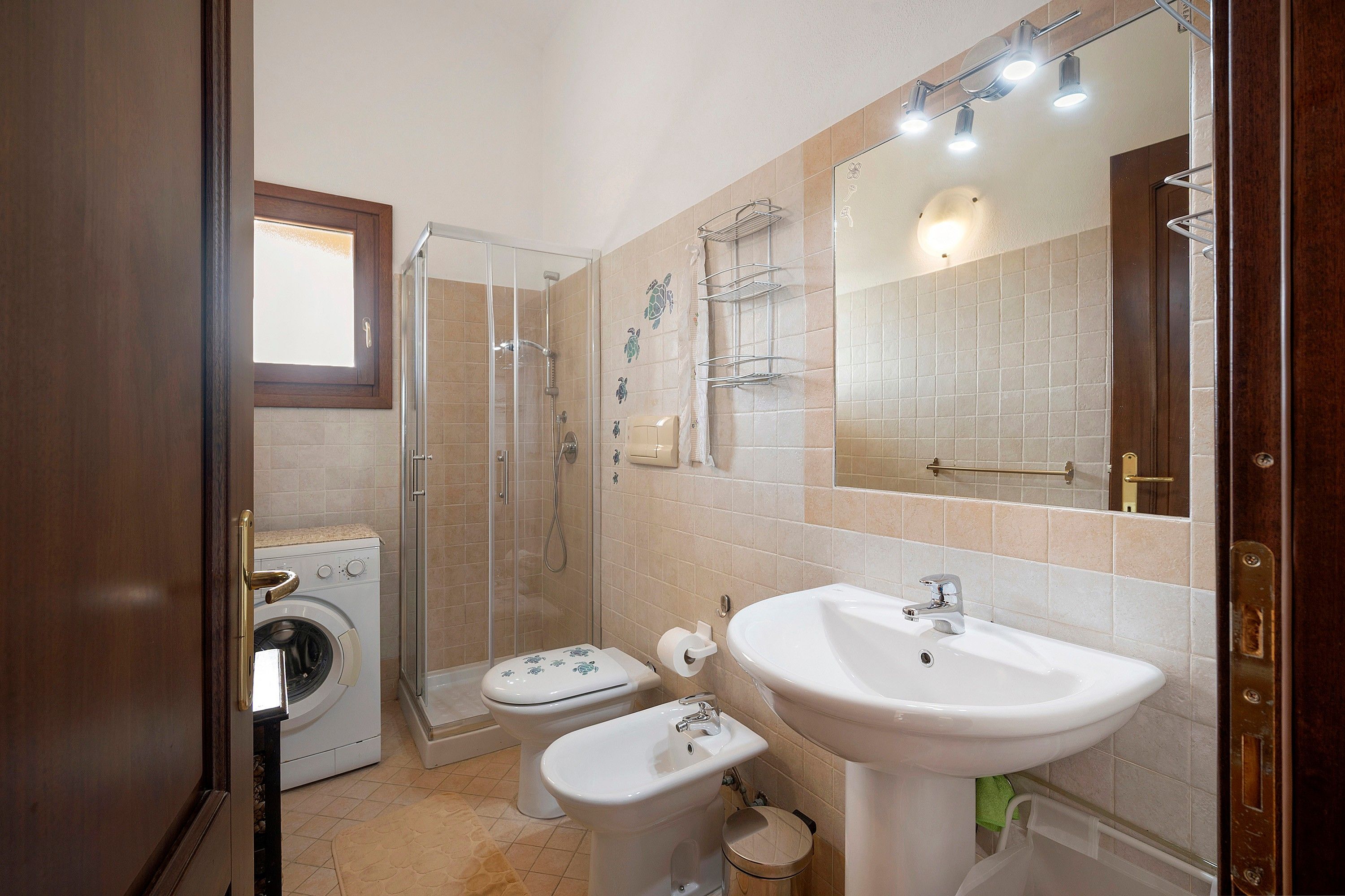 Une petite salle de bain équipée d’un lave-linge, de toilettes, d’un bidet et d’un lavabo.
