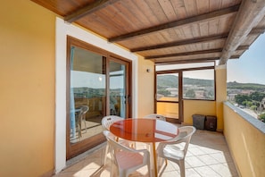 A balcony with a table and chairs, a view of the city, and a wooden ceiling. - Apartment 'Casa Marco Polo' with Sea View, Balcony and Air Conditioning (Santa Teresa Gallura)