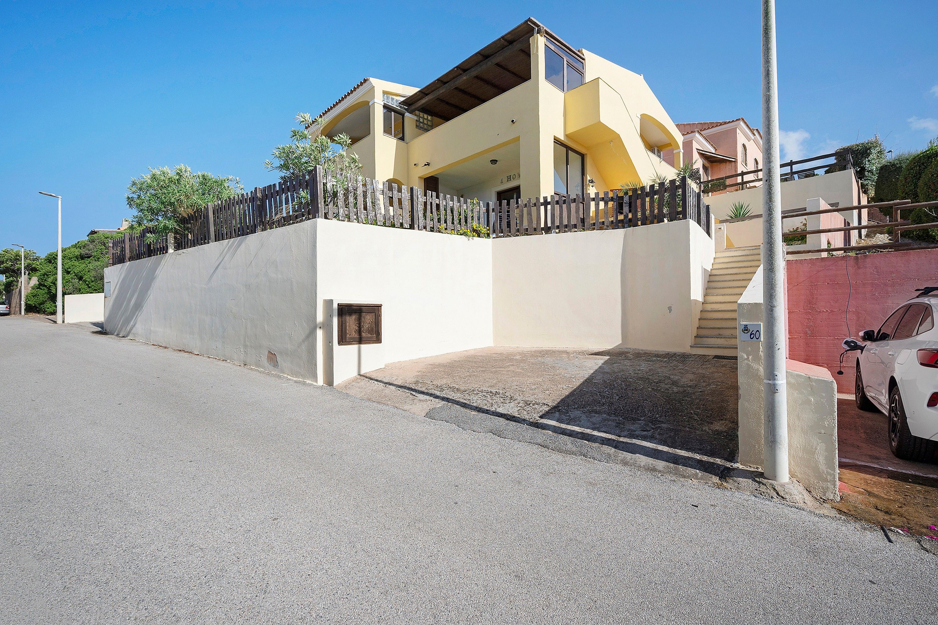 A two-story building with a balcony, a staircase, and a car parked in front.
