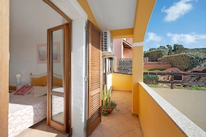 A balcony with a view of a hillside, a sliding door leading to a bedroom, and a potted plant. - Apartment 'Casa Marco Polo' with Sea View, Balcony and Air Conditioning (Santa Teresa Gallura)