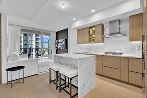 A modern kitchen with a marble countertop, wooden cabinets, and a built-in stove.