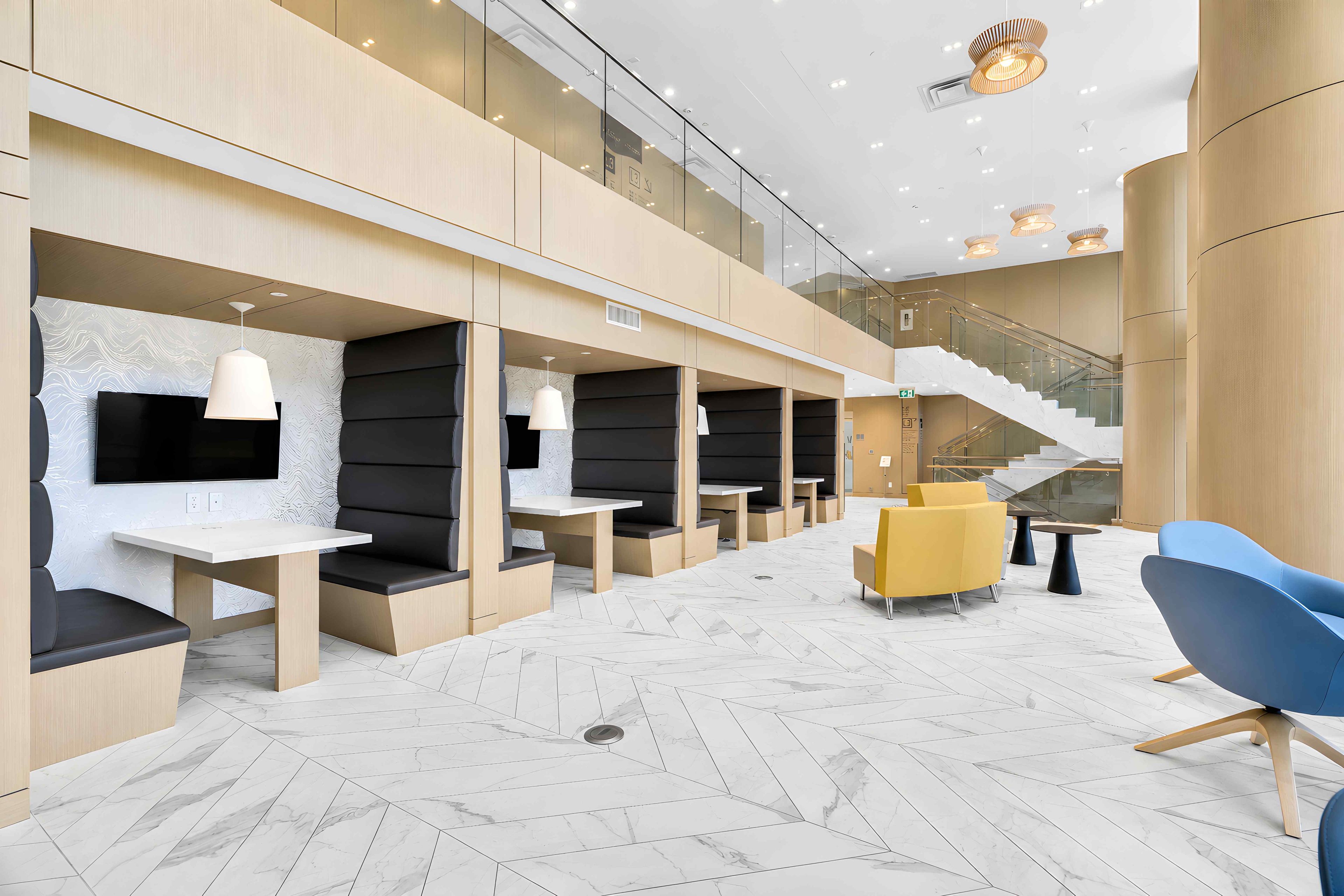 A modern interior with seating areas, a staircase, and a herringbone-patterned floor.