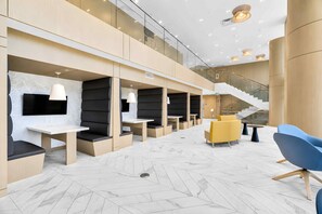 A modern interior with seating areas, a staircase, and a herringbone-patterned floor.