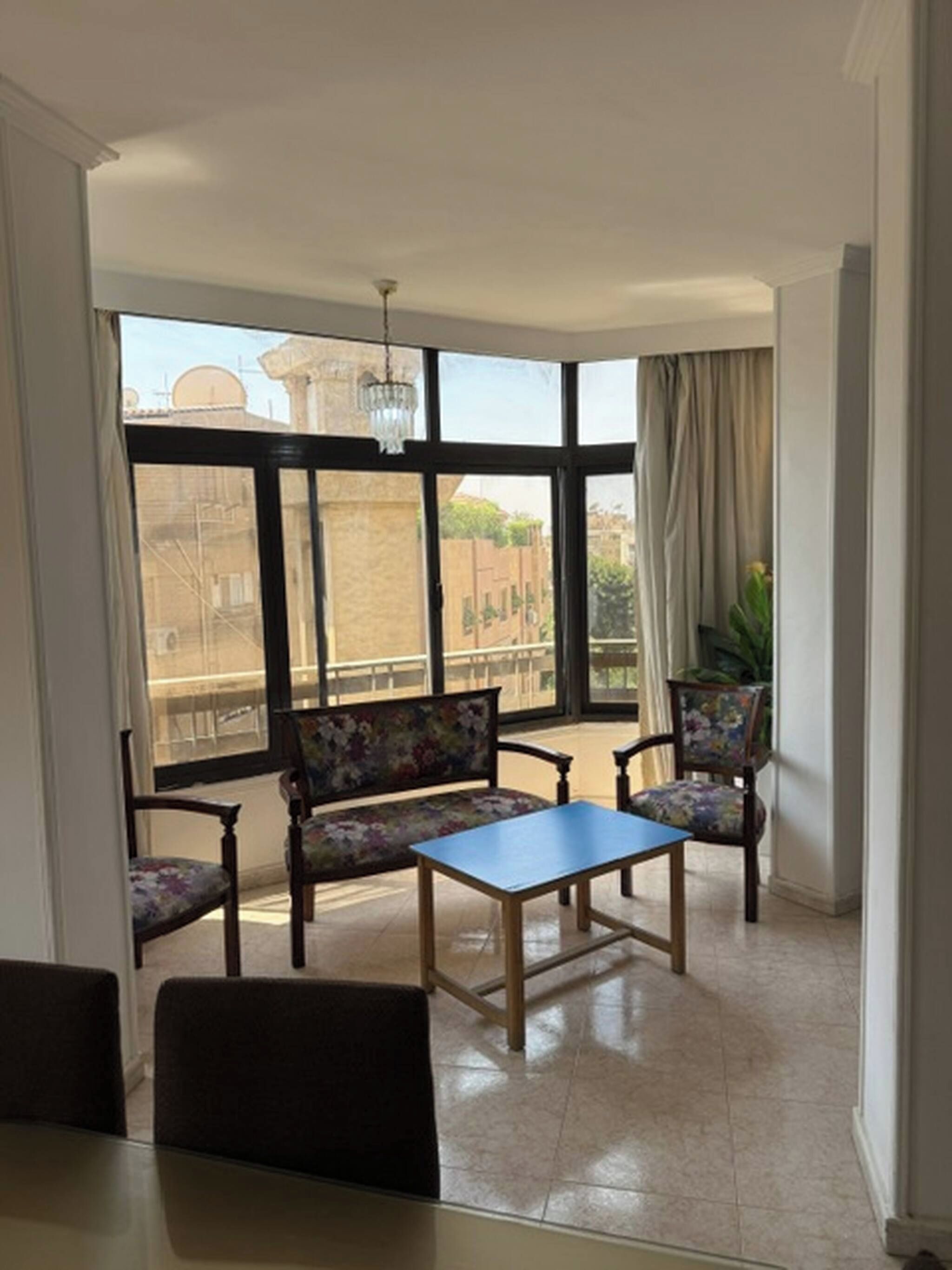 A room with a large window, a table, two chairs, and a bench.
