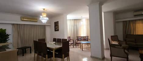 A spacious living area with a dining table, chairs, a sofa, and a coffee table.