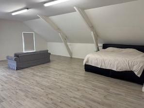 A room with a bed, a sofa, and a window.
