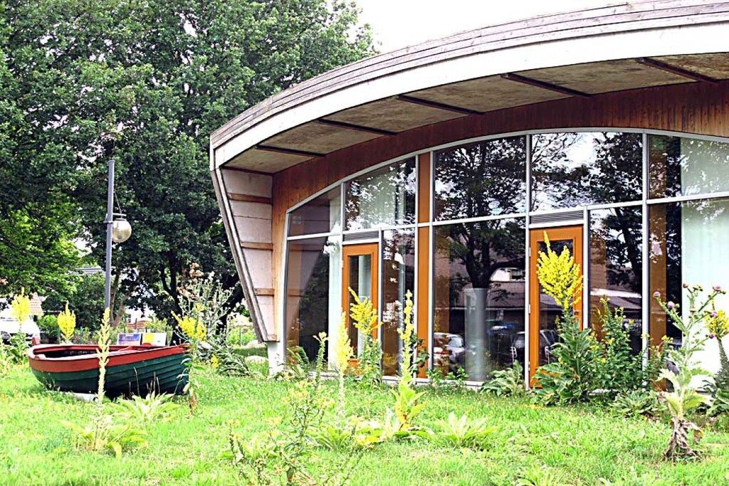 Un bâtiment moderne doté de grandes fenêtres et d’un toit incurvé.