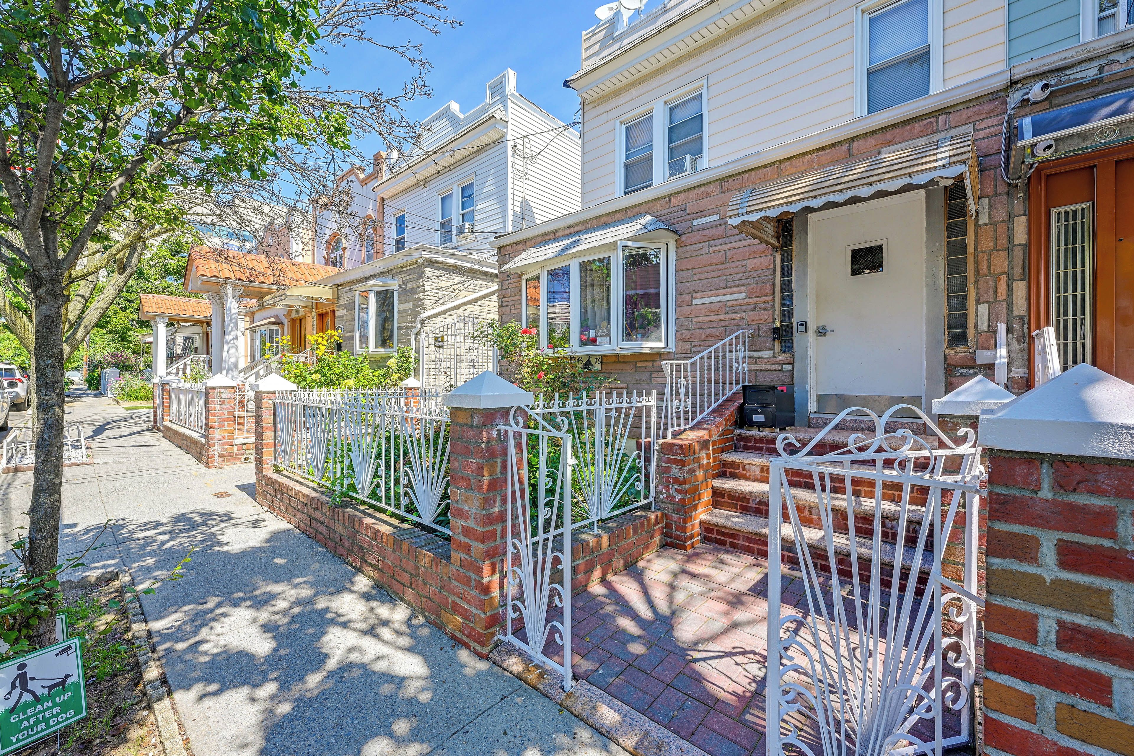 A row of townhouses with brick facades, white railings, and a clear sky.