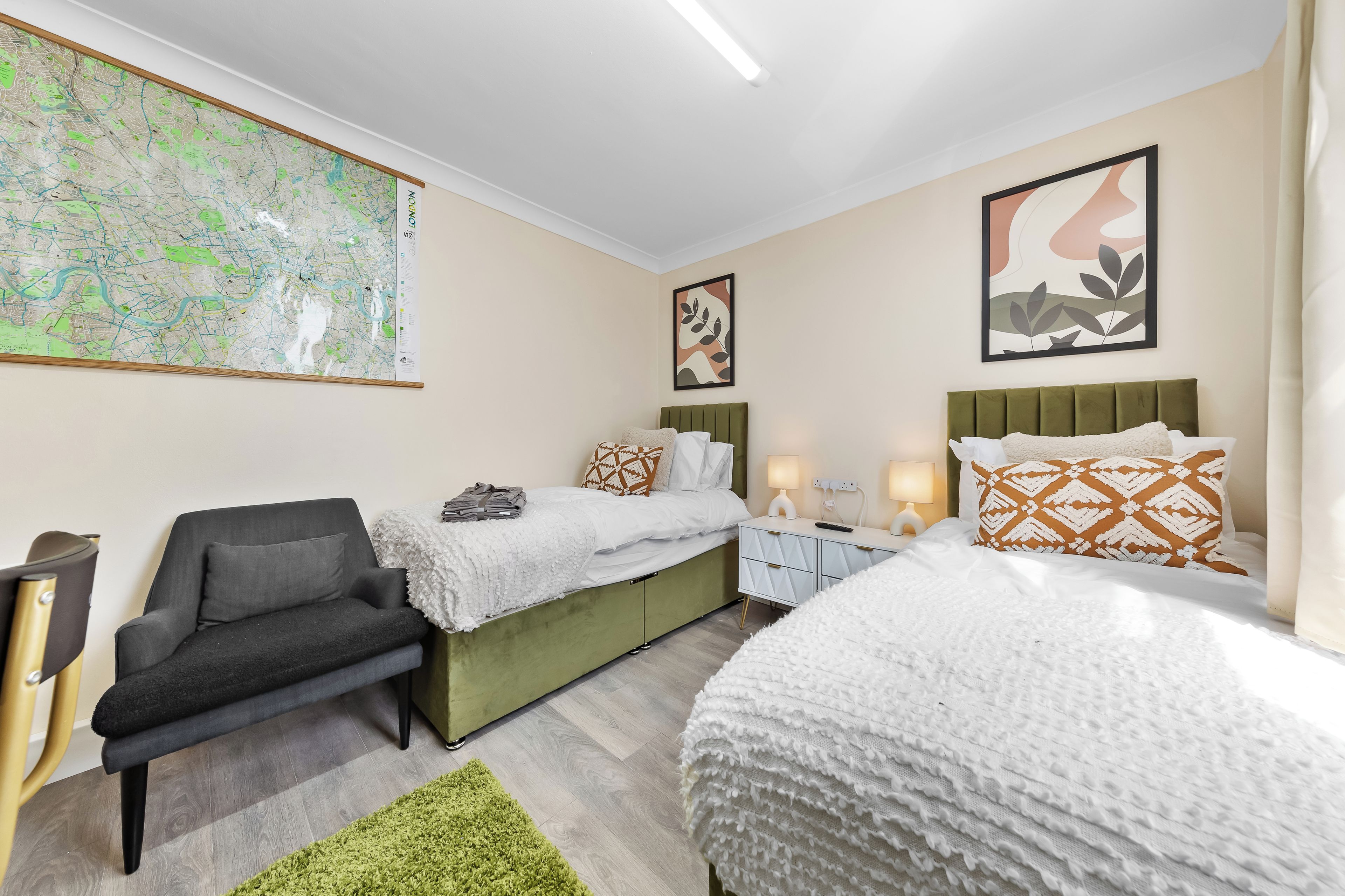 Quarto de hotel com um mapa grande na parede, duas camas, um sofá e um tapete verde.