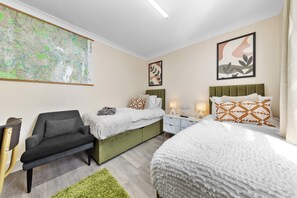 A hotel room with a large map on the wall, two beds, a sofa, and a green rug. - Leyton 1BR Flat | Near Tube, 247 Gym, Tennis Court (Greater London)