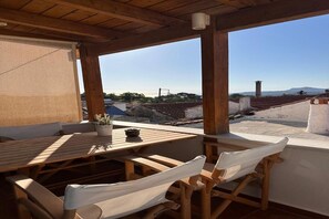 Un tavolo e sedie in legno su un balcone con vista su edifici e montagne.