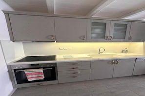 Una cucina con mobili grigi, un forno in acciaio inossidabile, un lavandino e uno scolapiatti.