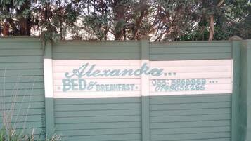 Une porte verte avec une enseigne indiquant « Alexandra Bed & Breakfast », ainsi qu’un numéro de téléphone.