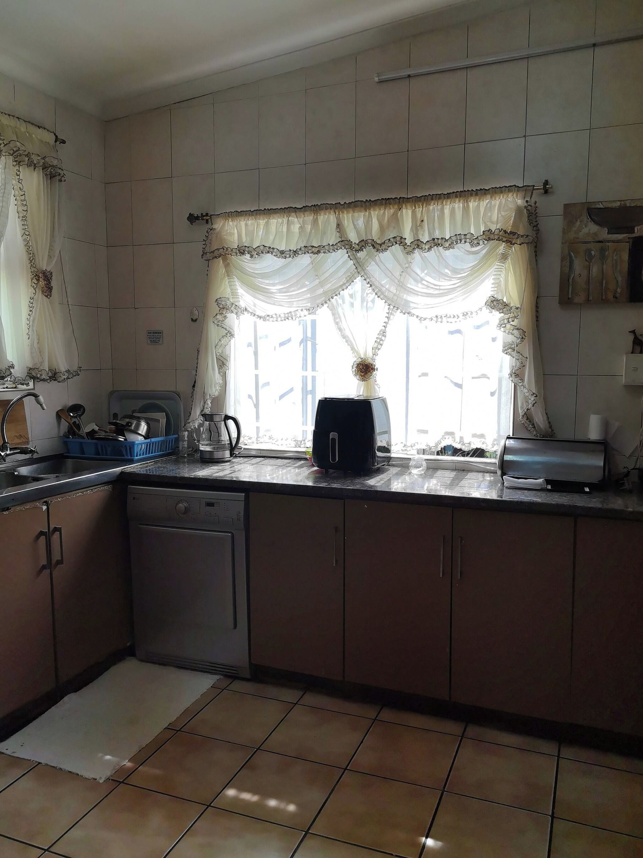 A kitchen with a dishwasher, a coffee maker, and a toaster on the counter.
