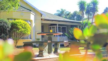 A building with a porch and a fountain in the foreground.