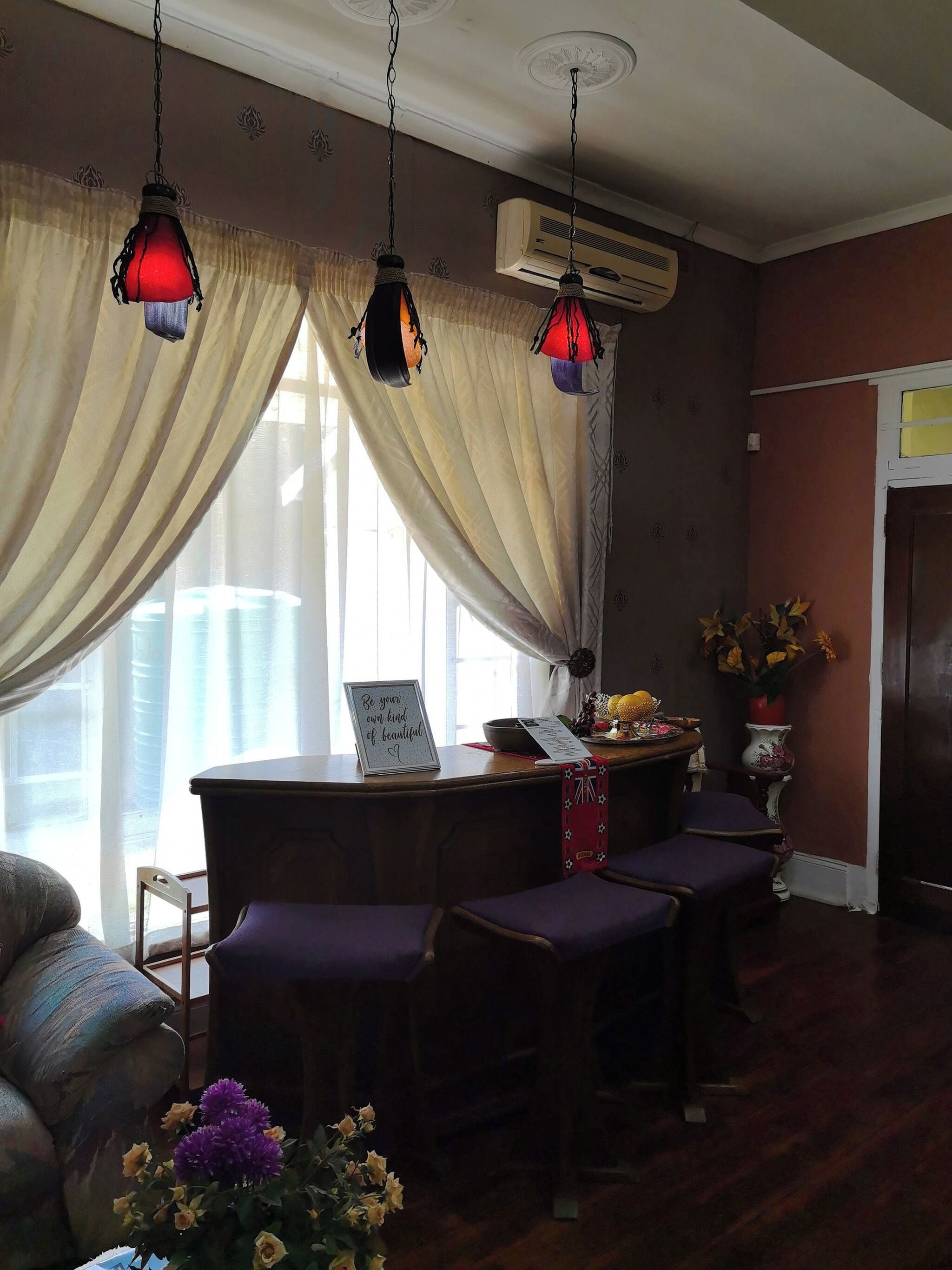 Una habitación con una mesa de comedor, sillas moradas, un jarrón decorativo y un equipo de aire acondicionado.