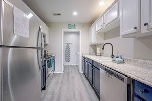 A modern kitchen with stainless steel appliances, a sink, and a door marked 'Eat'. - Perfect Location! Amazing Views & Close to It All! (Branson)
