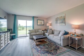 A living room with a sofa, a coffee table, a TV, and a large window with curtains. - Perfect Location! Amazing Views & Close to It All! (Branson)