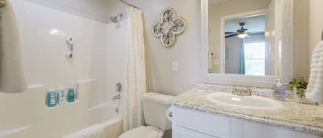 Un baño con ducha, inodoro, lavabo y espejo.