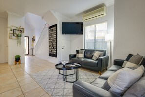 Una sala de estar moderna con un sofá gris, una mesa de centro negra y un televisor montado en la pared.