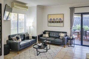 A living room with two leather sofas, a coffee table, and a painting on the wall. - `Dunsborough`s Doorstep` Townhouse Great Location (Dunsborough)