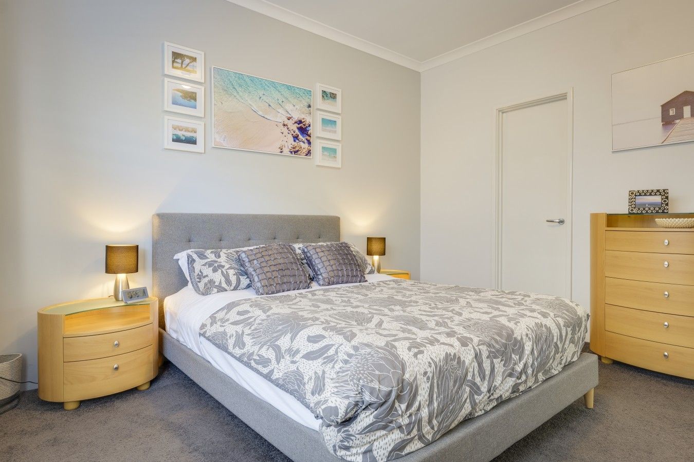A bedroom with a bed, two bedside tables, a dresser, and wall art.