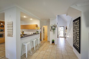 A spacious kitchen with a central island, white bar stools, and a view into the dining area. - `Dunsborough`s Doorstep` Townhouse Great Location (Dunsborough)