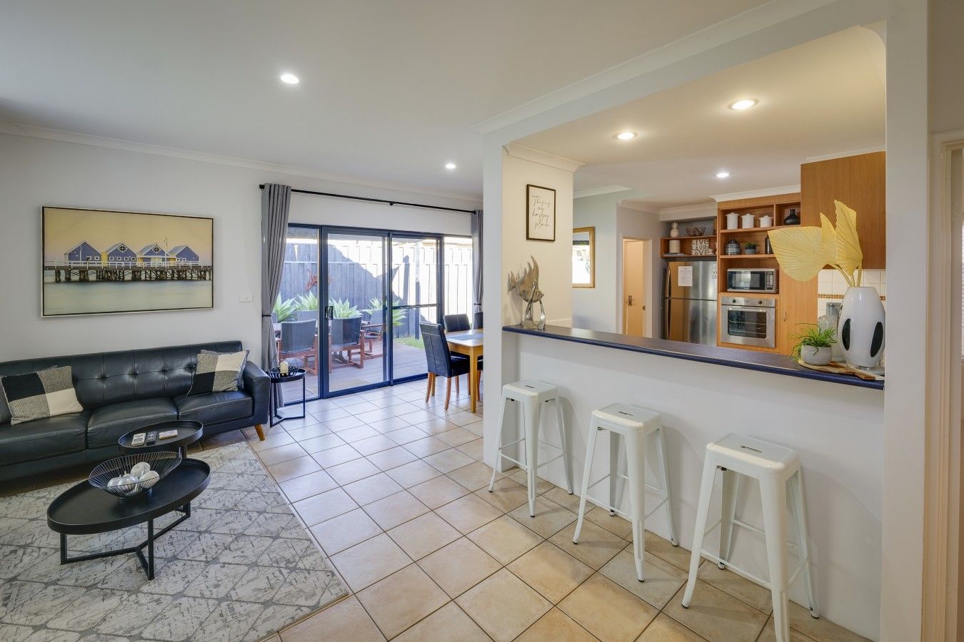 A living room with a sofa, coffee table, and a dining area with stools.